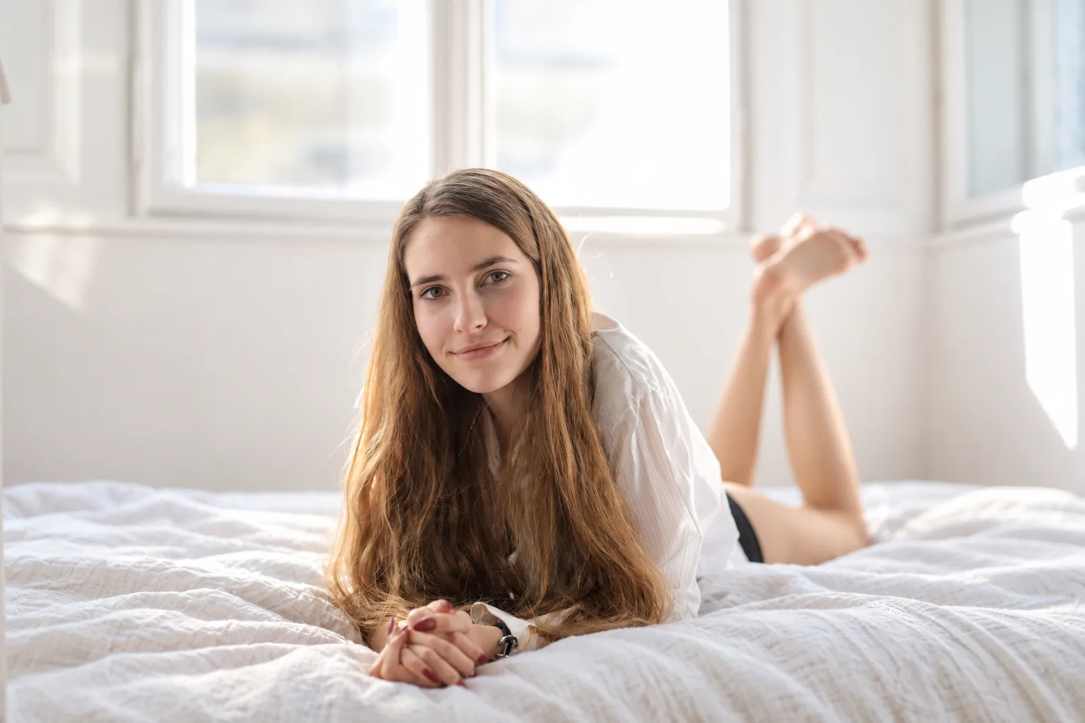 A woman lying on a tidy bed, smiling